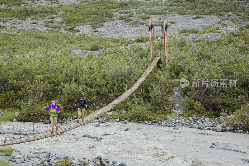 背包客徒步穿越阿拉斯加河上的吊桥