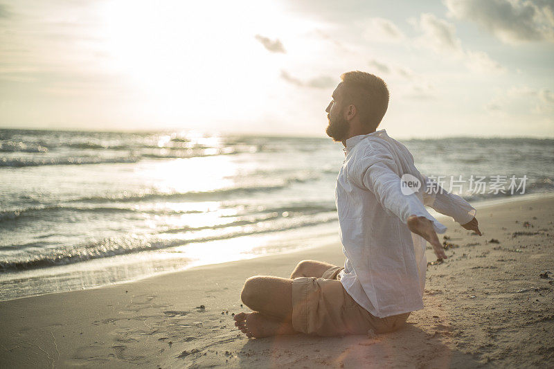 海滩上的男人一边放松一边练瑜伽
