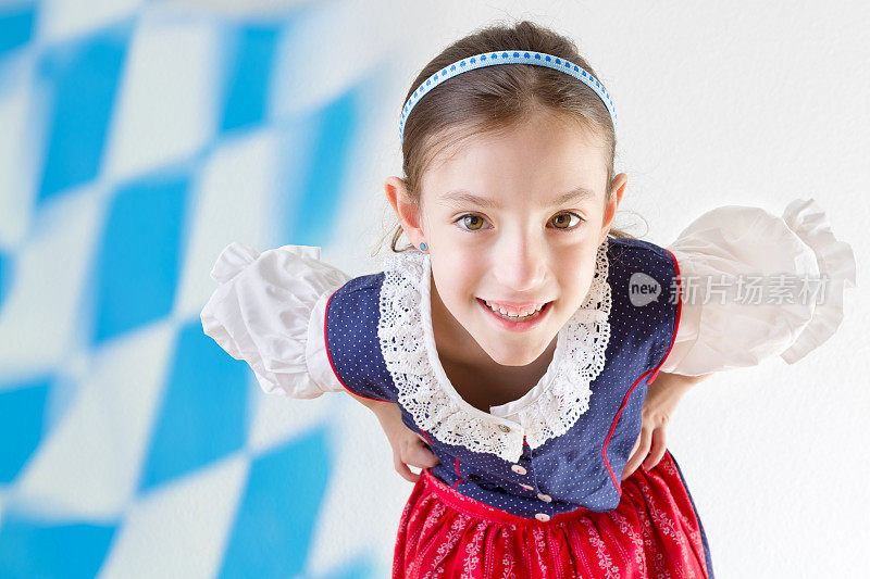巴伐利亚小女孩穿着传统的连衣裙，叫做连衣裙和巴伐利亚旗帜
