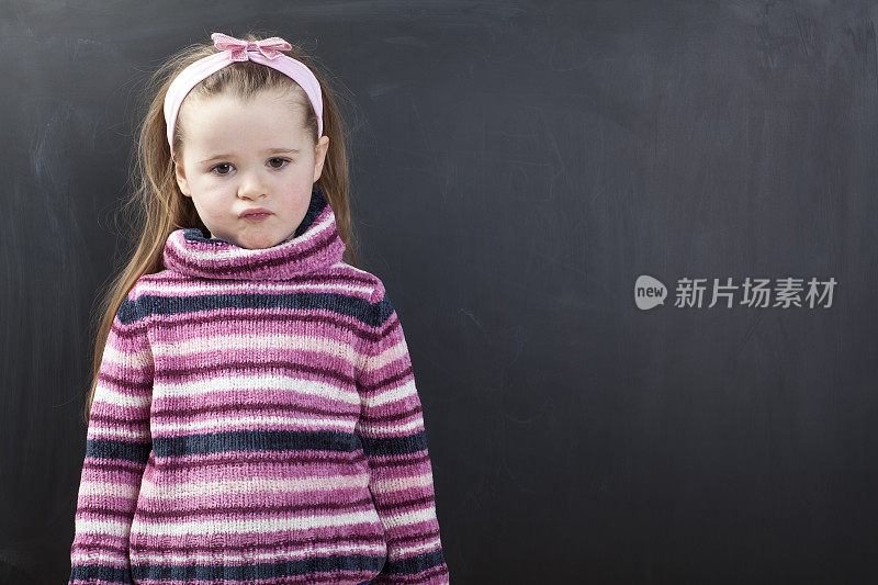 可爱的女孩站在黑板前