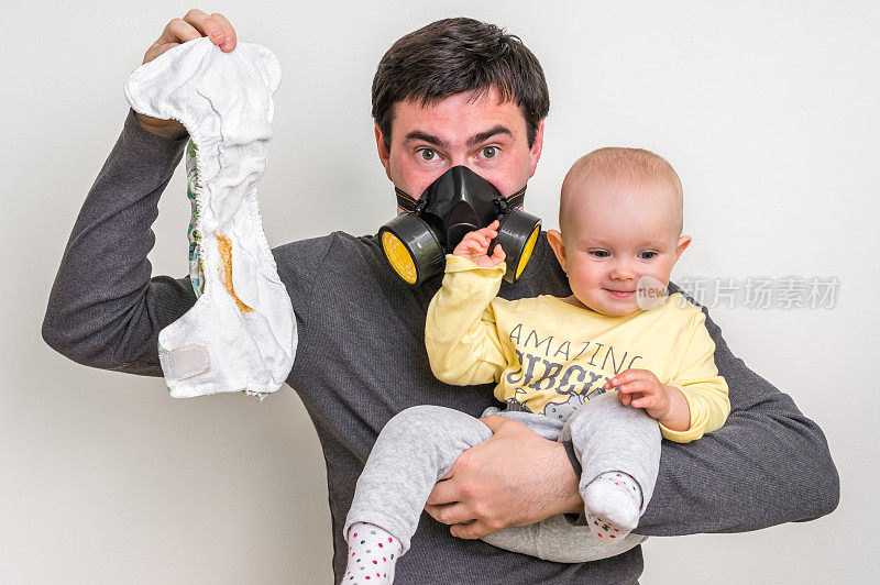 戴着防毒面具的爸爸抱着脏尿布和小婴儿