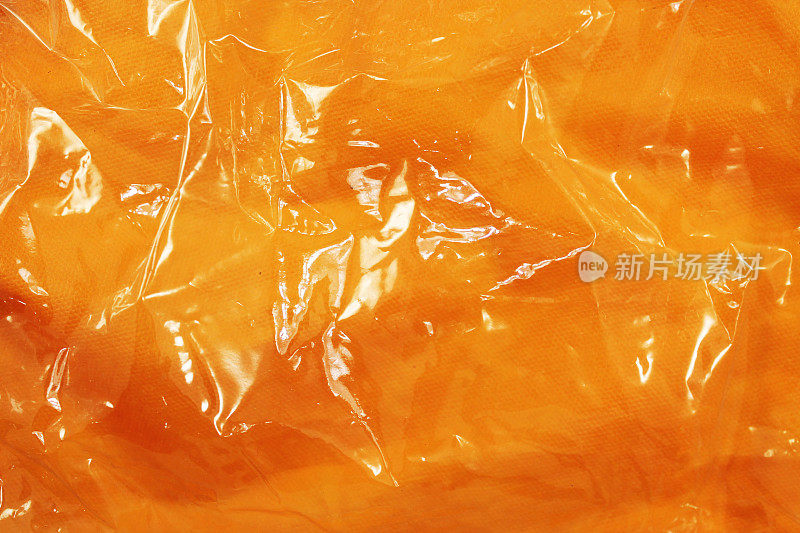 橙色塑料像乳胶一样闪闪发光。透明橡胶特写的橙色与闪光从光。乳胶质地的爱和性