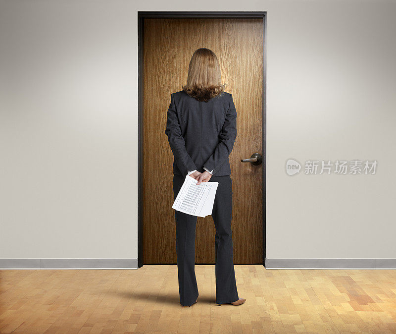 女商人站在办公室门前，背后拿着文件