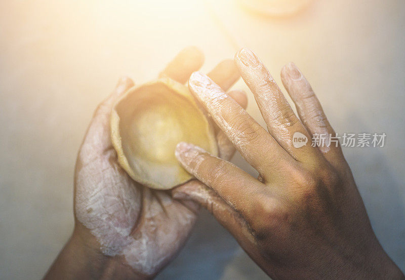 女陶工用粘土，手艺人的手制作陶器。顶视图的成型形状，以粘土碗由手指，光效果