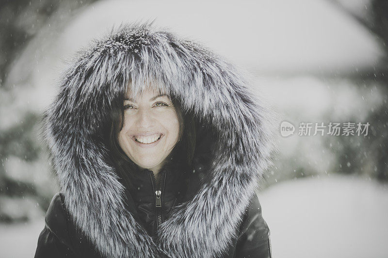 年轻漂亮的女子在暴风雪中穿着皮大衣