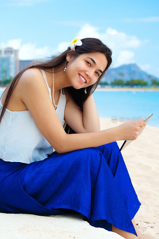 一名少女坐在夏威夷海滩上，背景是钻石头
