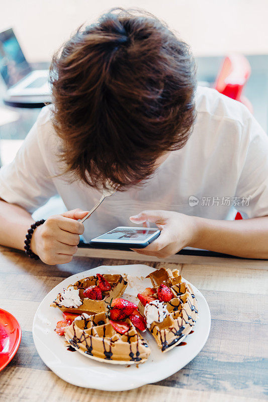 亚洲少年使用智能手机和在咖啡馆吃饭，上海。