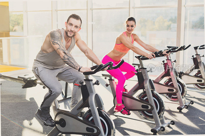一男一女，一对情侣在健身房里骑自行车