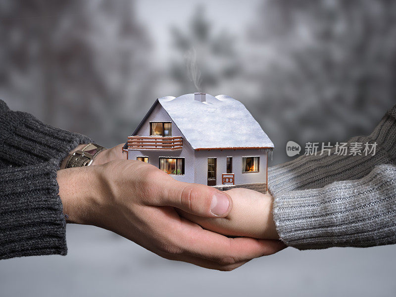 一个大人和一个孩子的手握着一个美丽的房子。私房的概念，买个乡村房子