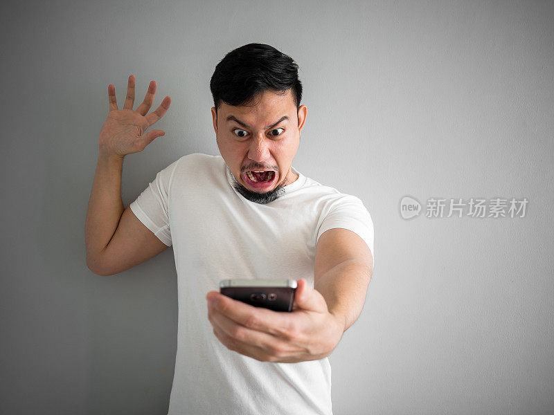 震惊和可怕的脸的男人从智能手机大喊。看看智能手机的可怕之处。