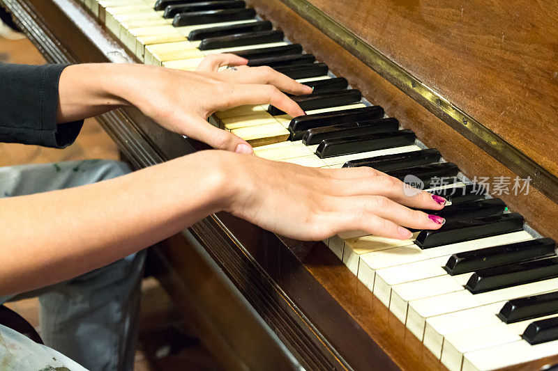 一只女人的手在弹奏一架老式钢琴。