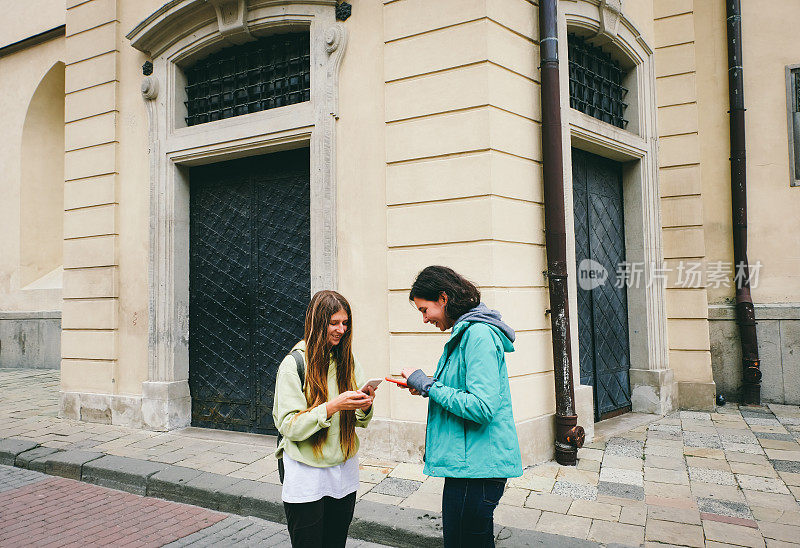 两个混血女孩一边旅行一边看智能手机