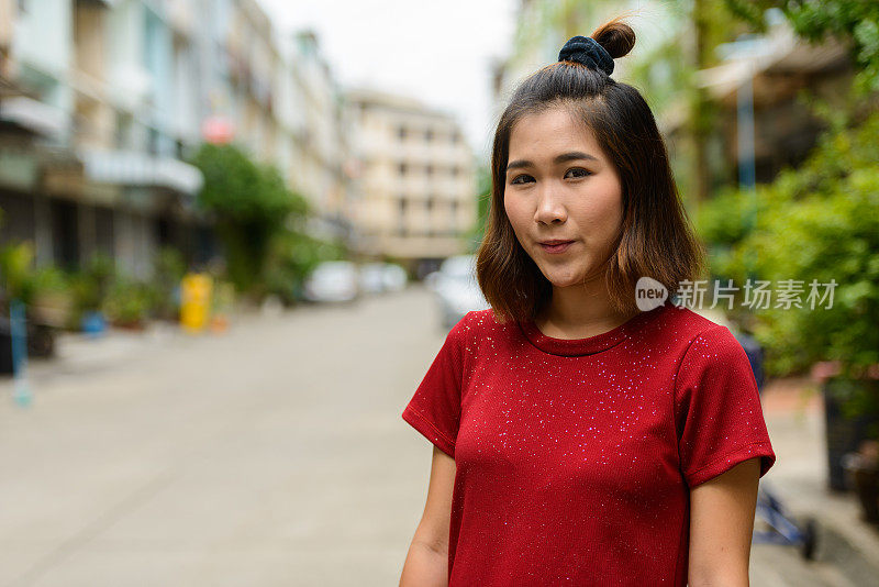 年轻的亚洲妇女穿着红色的衬衫在街上穿衣服
