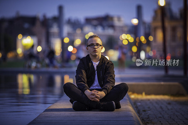 一个少年坐在阿姆斯特丹国立博物馆旁边的广场上