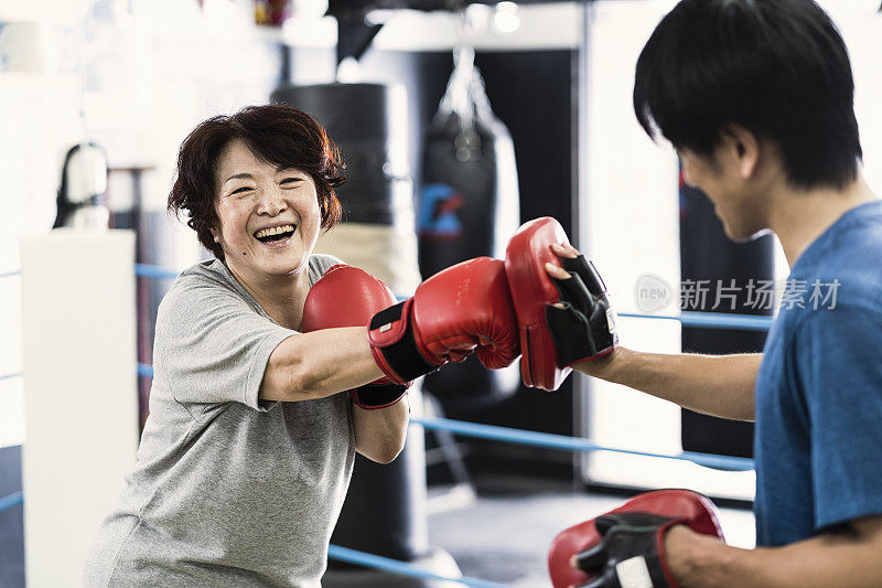 年长的成年女性在拳击馆里接受男性教练的训练