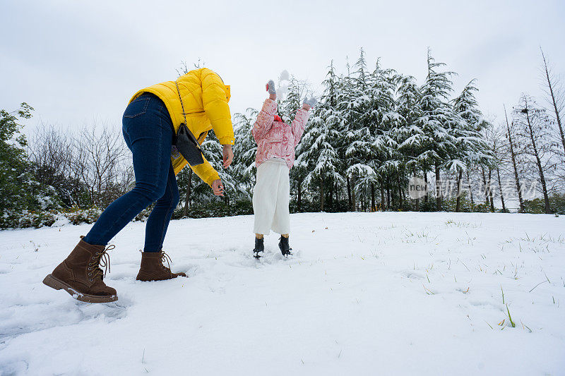 一个小女孩和妈妈在雪中玩耍