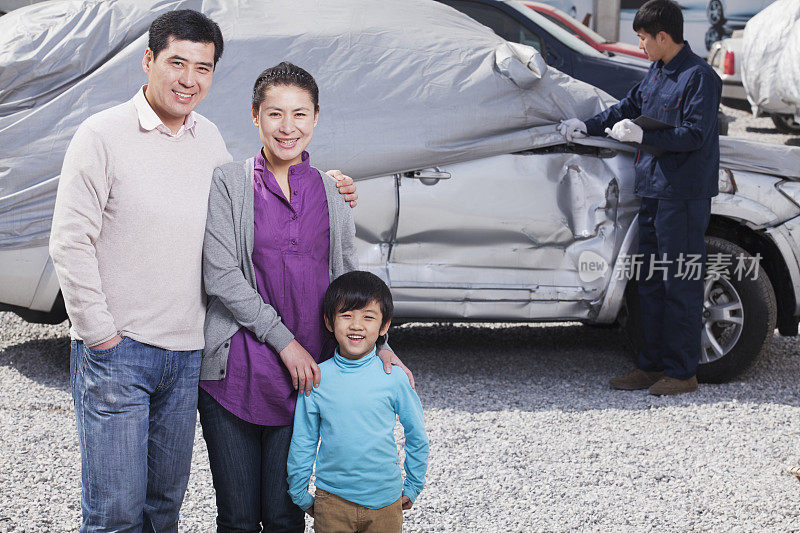 一个中国家庭站在毁坏的汽车前