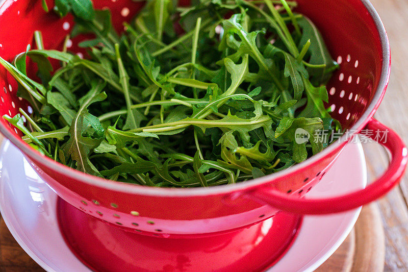 用滤锅用水冲洗新鲜的火箭叶子，特写