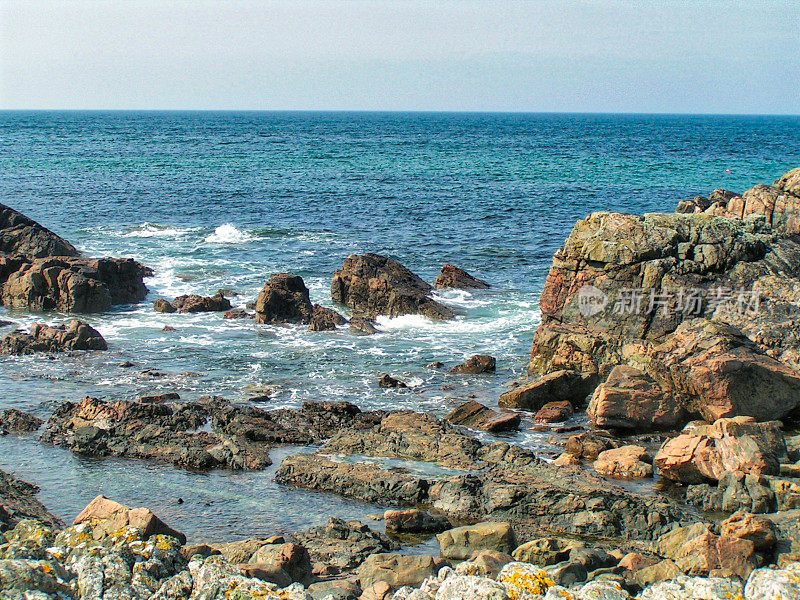 岩石嶙峋的海岸线，海浪轻轻拍打着岩石