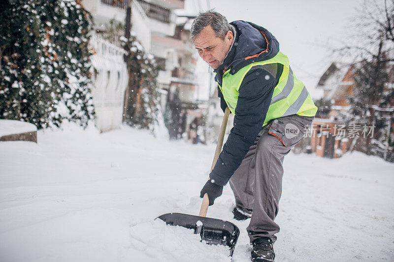 老人在清扫街上的积雪