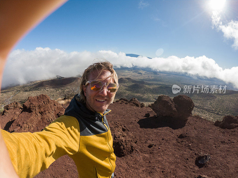 一个快乐的年轻人在日落时在火山上的云层上自拍