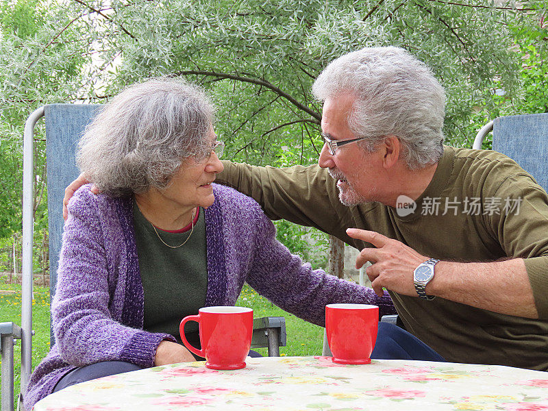 一对活跃的老夫妇在房子的后院喝清晨咖啡