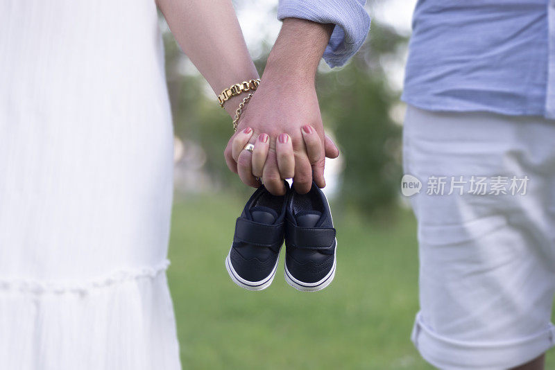 年轻父母候选人抱着一双未出生婴儿的小鞋子的腹部视图