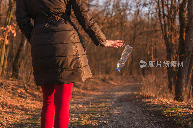 女人在大自然中丢弃塑料瓶。环境问题。