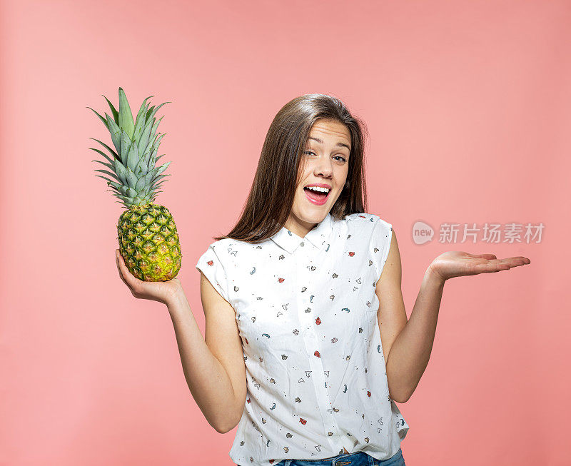 年轻女子一手拿着菠萝，用空手保持平衡