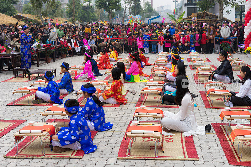 越南河内——2015年2月7日:在越南首都河内明开文中学举办的农历新年庆祝活动上，身着传统服饰的学生们正在学习书法