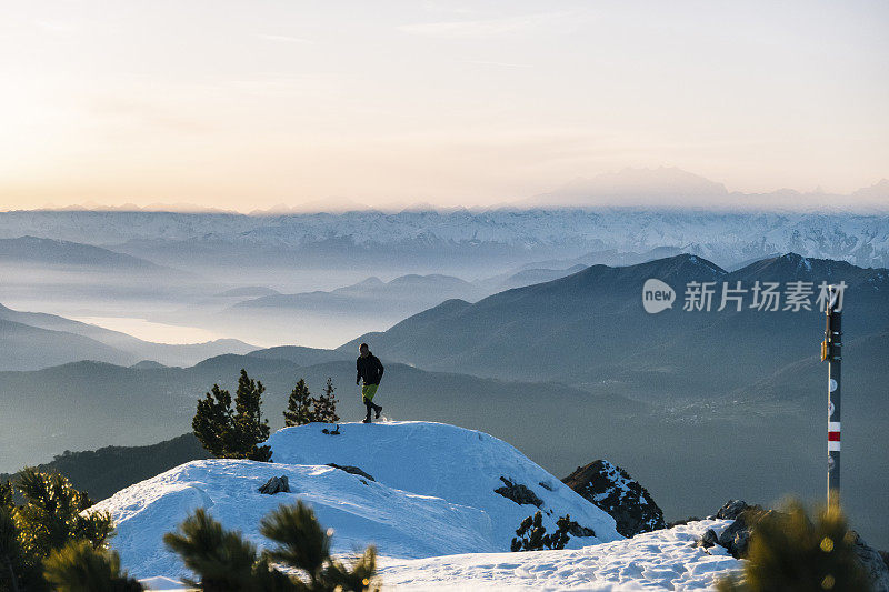 黎明时分，一名徒步运动员爬上雪山的山脊
