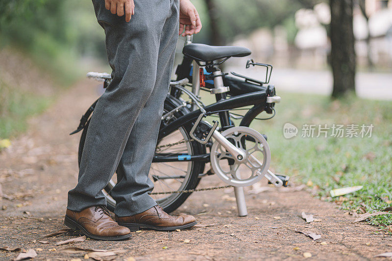一位亚洲华人白领管理人员骑着折叠自行车上下班