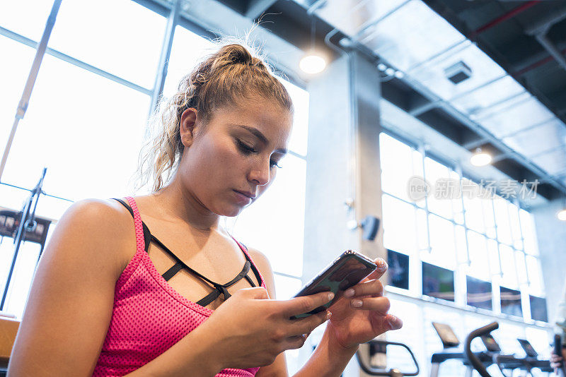 一个在健身房用手机查看社交网络的拉丁女人