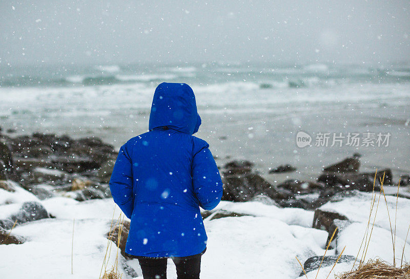 俯瞰挪威罗浮敦白雪覆盖的海滩的女人。