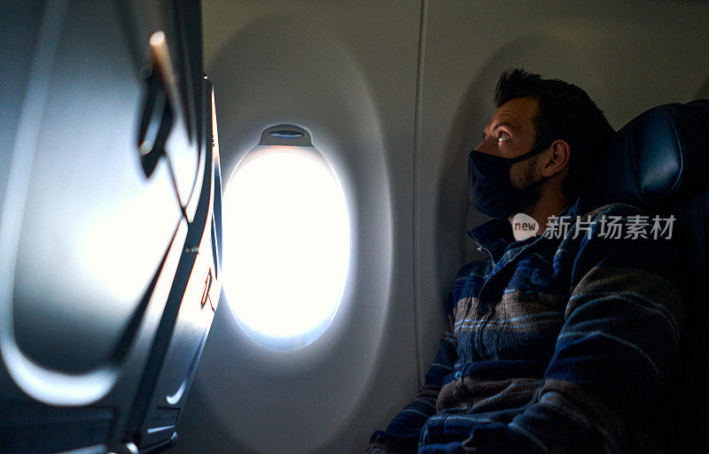 冠状病毒大流行期间，戴面罩坐在飞机上的年轻乘客