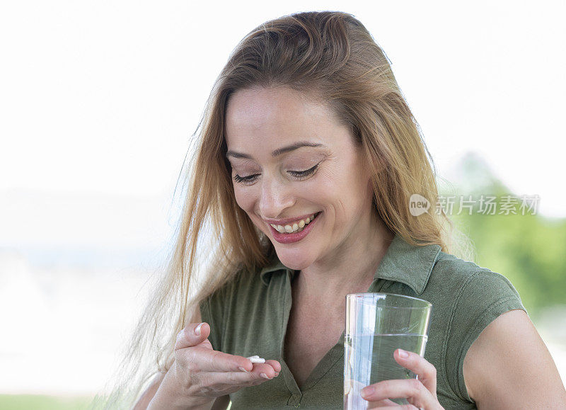 女人微笑着看着手里的维生素