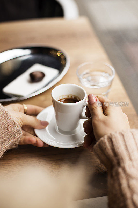 咖啡杯，女士的手拿着咖啡杯，女士拿着一个白色的杯子，咖啡在白色的杯子里