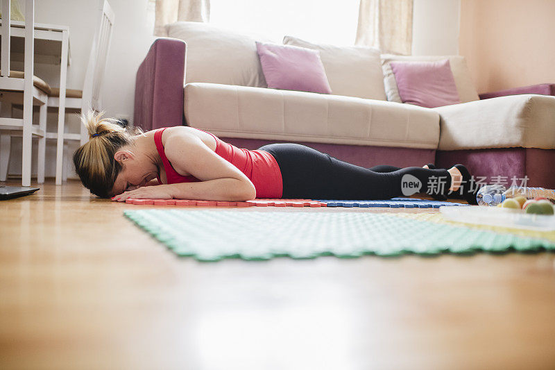 一个疲惫的女人在家锻炼后躺在地板上休息