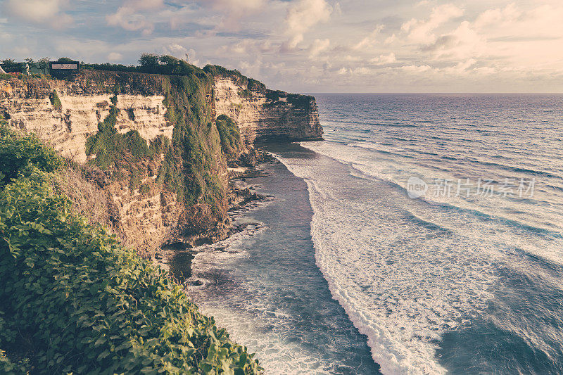 Uluwatu巴厘岛。蓝色的海洋和岩石山，覆盖着热带树木。