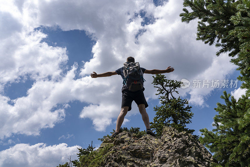 旅行者用背包跳跃的手举起山峦景观为背景生活方式旅行快乐情感成功概念夏日户外度假