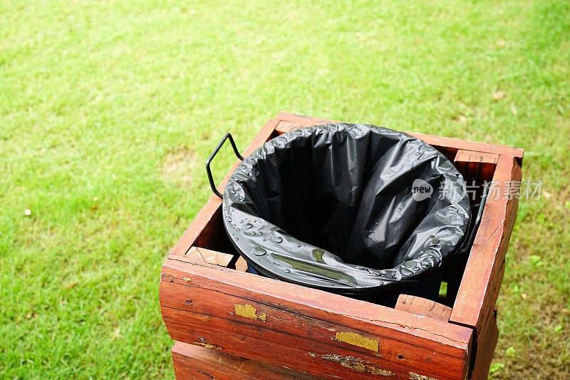 绿色草坪上的黑色塑料袋垃圾桶