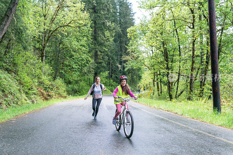 一个十来岁的女孩和她的家人在乡村公路上骑着自行车