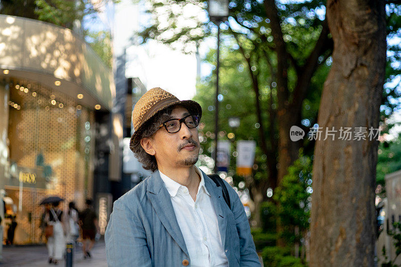 在东京表参道的一条绿树成荫的街道上，一位老人正在等待会议