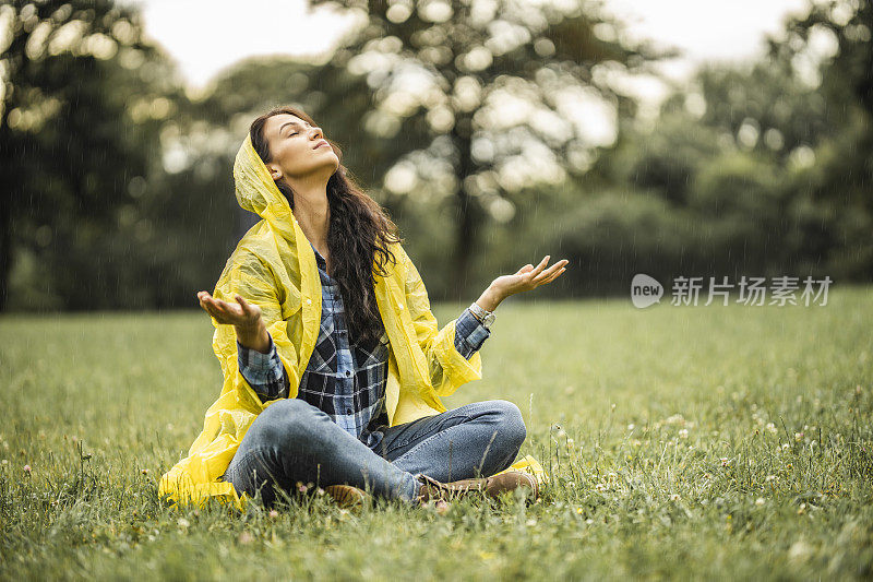 穿着黄色雨衣的女人，享受着雨的降临