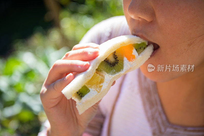 一位女士在一家日本便利店吃了一口水果三明治