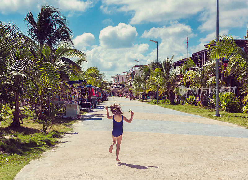 在墨西哥度假时，孩子在空旷的海滩大道上蹦蹦跳跳