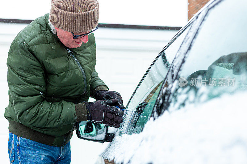 成年男子在冬天给汽车除冰