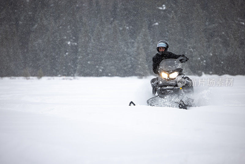 一名男子开着雪地摩托在粉状积雪中超速行驶