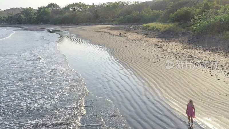 鸟瞰图的女人走下沙滩在日出