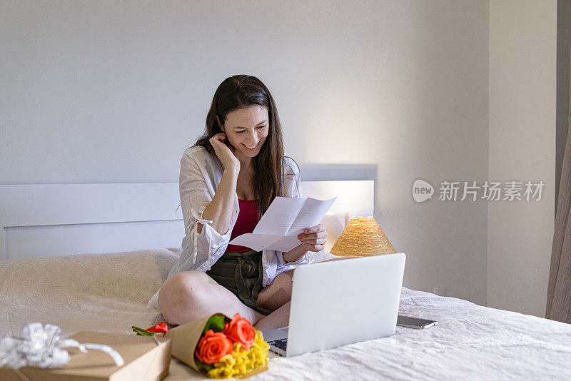 年轻女子在看男朋友寄来的浪漫情书时很开心